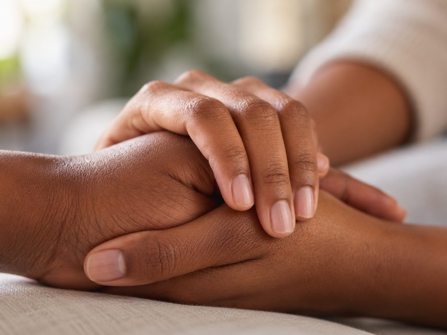 A carer gently holding the hands of the person they support